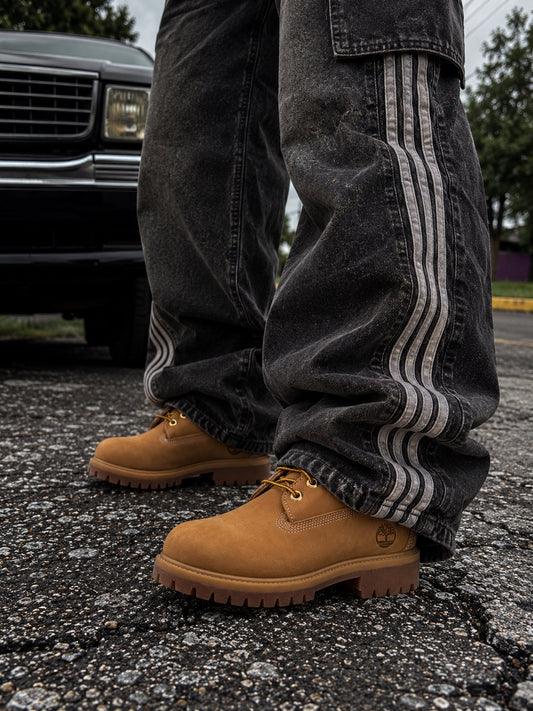 Detalle de botas Timberland camel unisex combinadas con pantalón baggy negro en exterior.