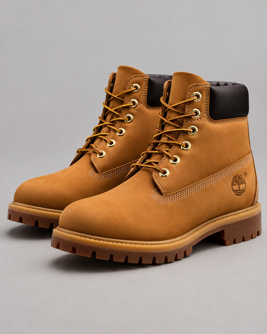Par de botas Timberland clásicas camel unisex sobre fondo gris, vista de tres cuartos.