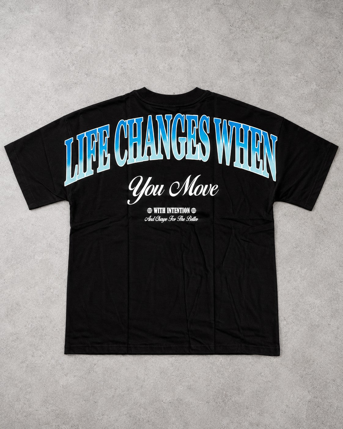 Playera Life Changes negra con frase Life Changes When You Move en azul en la espalda