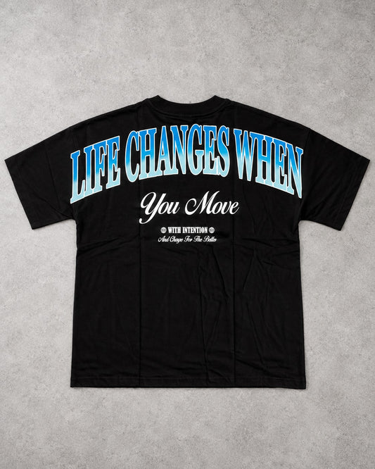 Playera Life Changes negra con frase Life Changes When You Move en azul en la espalda